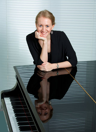 headshot of Elspeth leaning on a grand piano